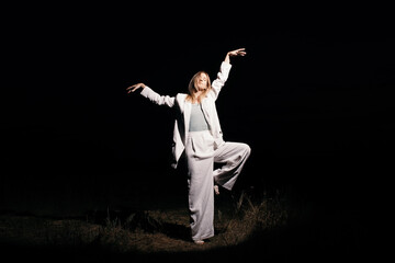 Woman in suit dancing in darkness