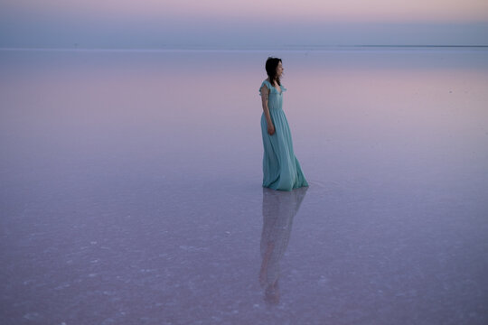 girl dress standing in pink water the sky is also pink