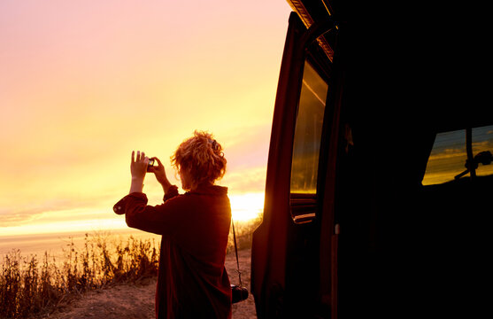 Wanderlust woman taking a picture of the sunset on a roadtrip through California
