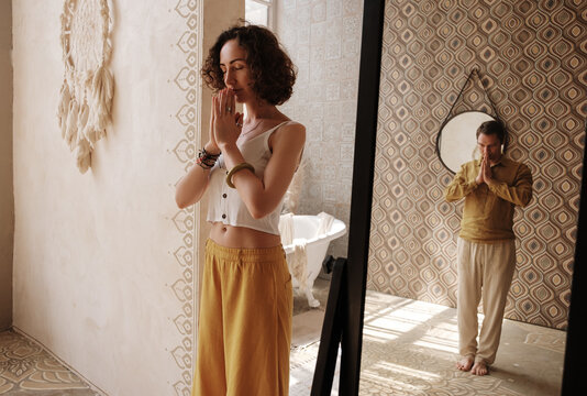 Female meditating with closed eyes near mirror with male reflection