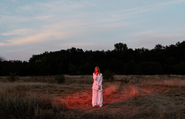 Colorful fashion portrait of trendy woman in minimalist clothes posing outdors under neon light
