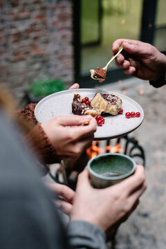 sharing a Christmas dessert with chocolate and red berries outdoors with a fire pit