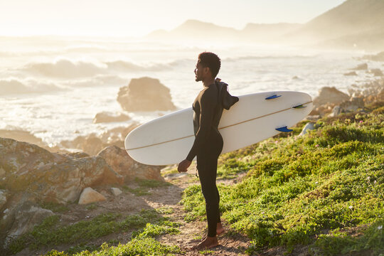 Surfer walking along a scenic coastline