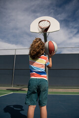 Cute smiling boy plays basketball. Active kids enjoying outdoor game with basket ball. Sport for kids.