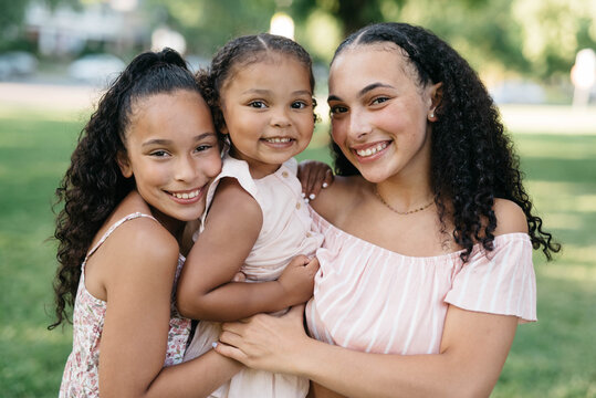 Three beautiful young mixed race sisters out in a park having fun