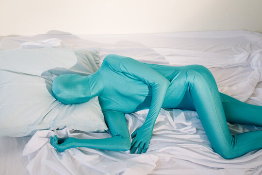 Anonymous person in odd colorful wear lying on bed