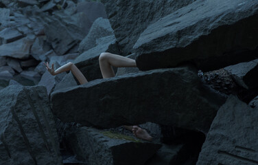 background of stones and two hands and a leg of a person peep out from them