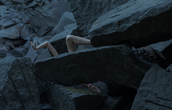 background of stones and two hands and a leg of a person peep out from them