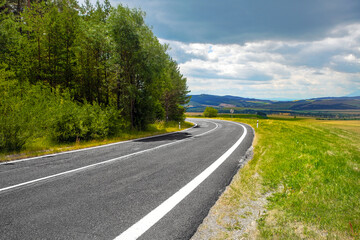 Asphalt road through green hills