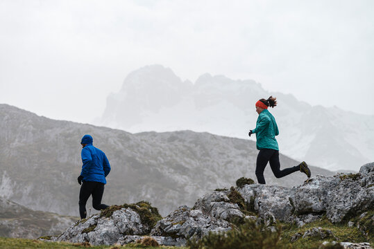 A young couple does mountain running or a trail run at mountains