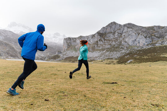 Side view of dynamic trail runners with warm clothes running outside