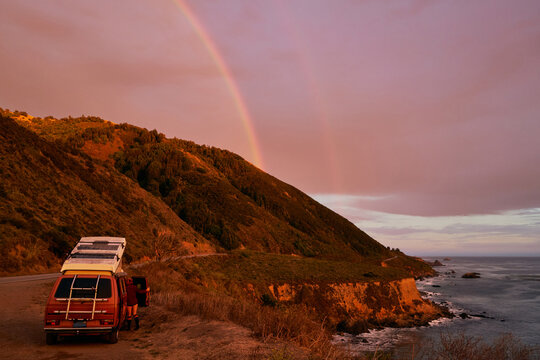 Van life Rainbow sunset moment with a vintage campervan and the magnificent views of the pacific west coast in California during a roadtrip. - Powered by Adobe
