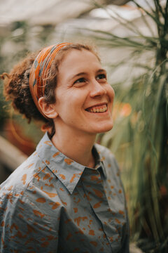 A beautiful curly woman in a green house smiling