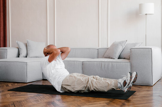 Senior man doing abdominal exercise at home