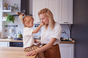 Young mother and her little daughter in the kitchen at home.