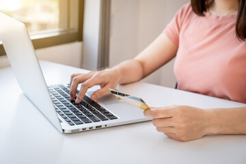Young Asian consumer woman hand holding a credit card, Ready to spending pay online shopping according to discount products via smartphone and laptop from home