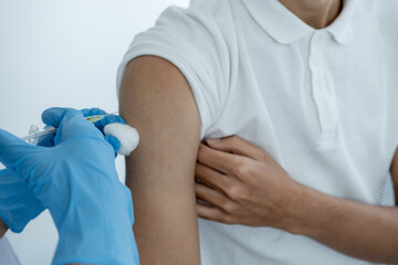 The doctor's hand holding a syringe and was about to vaccinate a patient in the clinic to prevent the spread of the virus