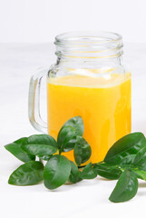 Orange juice and green leaves on a white background.A glass of orange juice and orange fruit. Healthy food. Vegan food. Diet and proper nutrition. Copy space. Place for text. Vertical orientation.