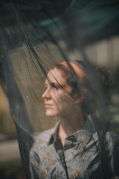 A Portrait of a beautiful woman behind a curtain
