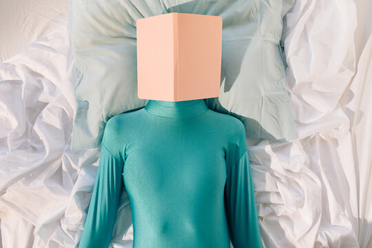 Unrecognizable woman with book resting on bed