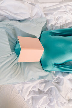 Unrecognizable woman with book resting on bed