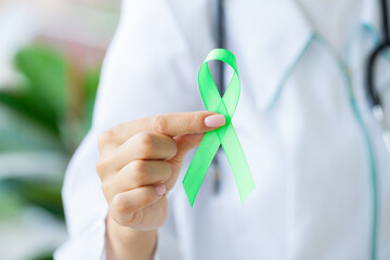 Green ribbon in hand as a symbol to awareness Lymphoma cancer