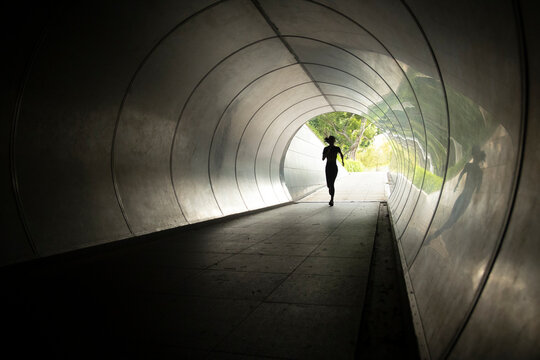 The silhouette of a runner as she passes through a tunnel in Singapore.