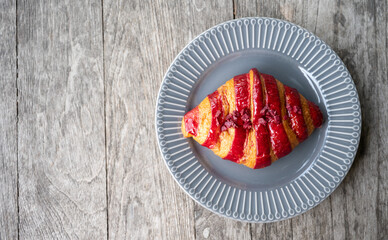 Top view of Raspberry Croissant on wooden table. Croissant is a French buttery, flaky and crescent-shaped bread.