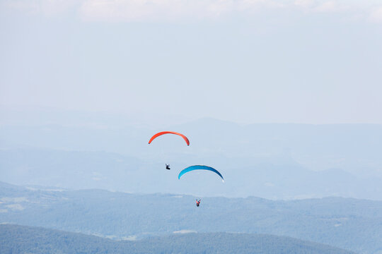 Two paragliders in the air over mountains