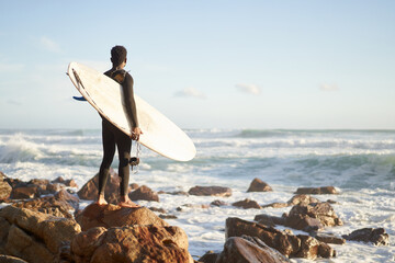 Surfer exploring rocky shoreline for surf