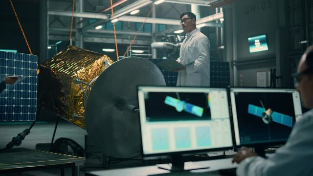 Team of Engineers Working on Satellite Construction. Aerospace Agency Spaceship Manufacturing Factory: Diverse Group of Multi-Ethnic Scientists Developing Spacecraft for International Space Program.