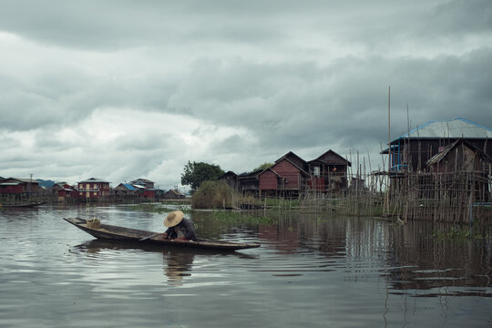 Man wearing a traditional Burmese hat seating in a boat