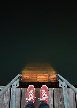 Top view at red sneakers on pier ladder leading down to deep wat