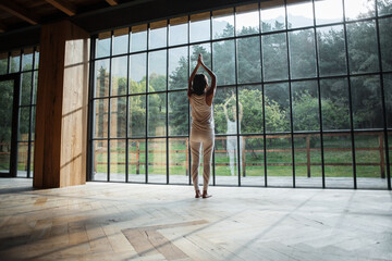 Anonymous female doing Urdhva Hastasana pose in spacious room
