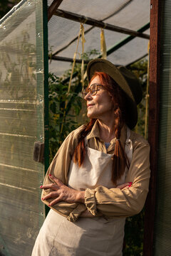 senior woman stands near the greenhouse
