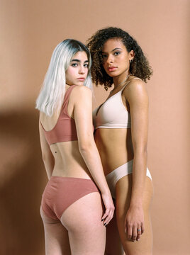 Slim women in sport underwear on brown background