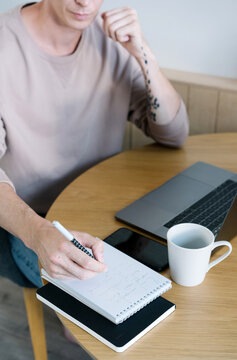 Crop modern guy writing on notepad