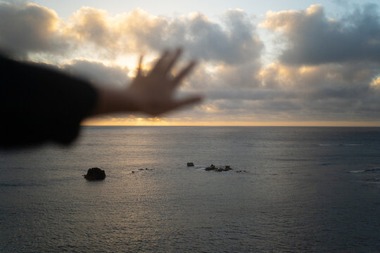 Hand And Seascape At Sunset.
