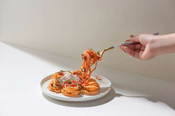 Fresh bite of hot spaghetti wrapped on fork against bright background. Shallow depth of field.