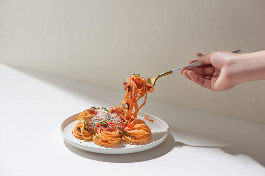 Fresh bite of hot spaghetti wrapped on fork against bright background. Shallow depth of field.