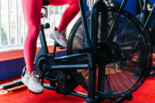 Crop women exercising on bikes in gym