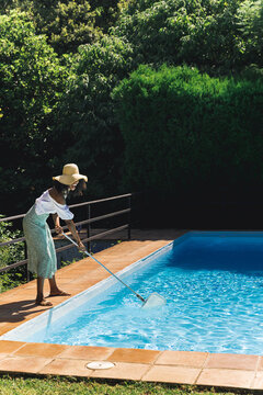 Woman cleaning pool in summer day