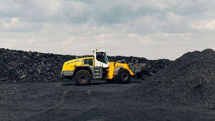Yellow bucket loader is working busy loading coal. Extraction of minerals.