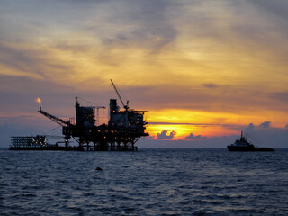Fototapeta na wymiar Oil and gas platform in open sea, producing crude oil and gas as a source of energy. Sunset moment in oil field.