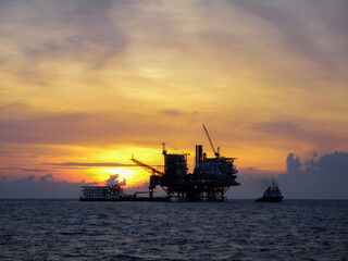 Fototapeta na wymiar Oil and gas platform in open sea, producing crude oil and gas as a source of energy. Sunset moment in oil field.