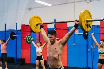 Sweaty sportsman lifting barbell in gym