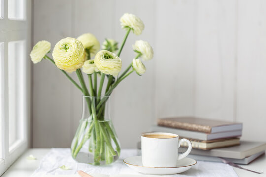 White ranunculus with coffee and books