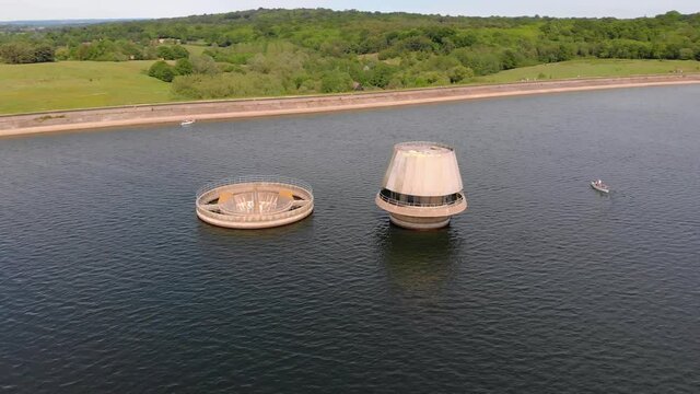 Draw-off tower and overflow tower at a reservoir. Draw-off tower releases water beyond the dam for a variety of uses. Aerial shot.