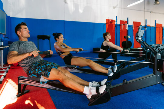 Determined athletes exercising on rowing machines