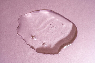 A drop of transparent cosmetic gel on a pink background